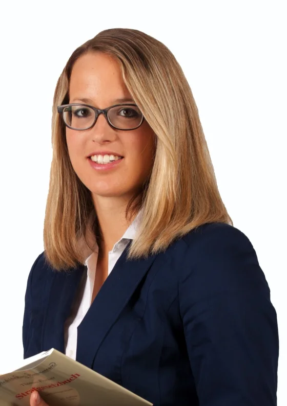 Rechtsanwältin Bettina Anselstetter mit einem Strafgesetzbuch, Portraitaufnahme vor hellem Hintergrund