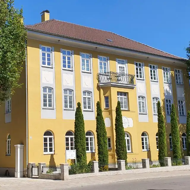 Frontansicht des Kanzleigebäudes mit schmiedeeisernem Balkon und Rundbogenfenstern im Erdgeschoss