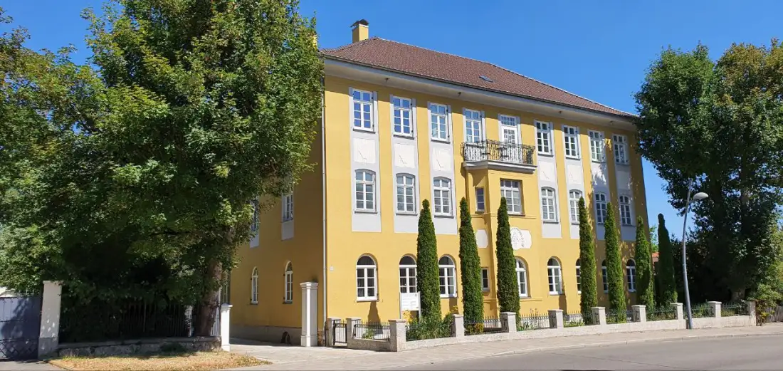 Das Kanzleigebäude von der Straßenseite, eingerahmt von altem Baumbestand