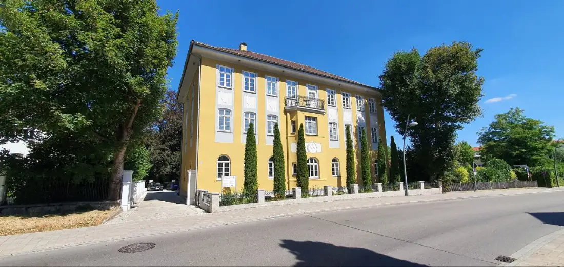 Das Kanzleigebäude von Kremnitz & Partner in der Bgm.-Reiger-Straße in Nördlingen: ein gelber Altbau mit Ziegeldach und Säulenzypressen davor
